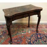 An 18th Century walnut veneered card table, the shaped top quartered,