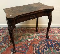 An 18th Century walnut veneered card table, the shaped top quartered,