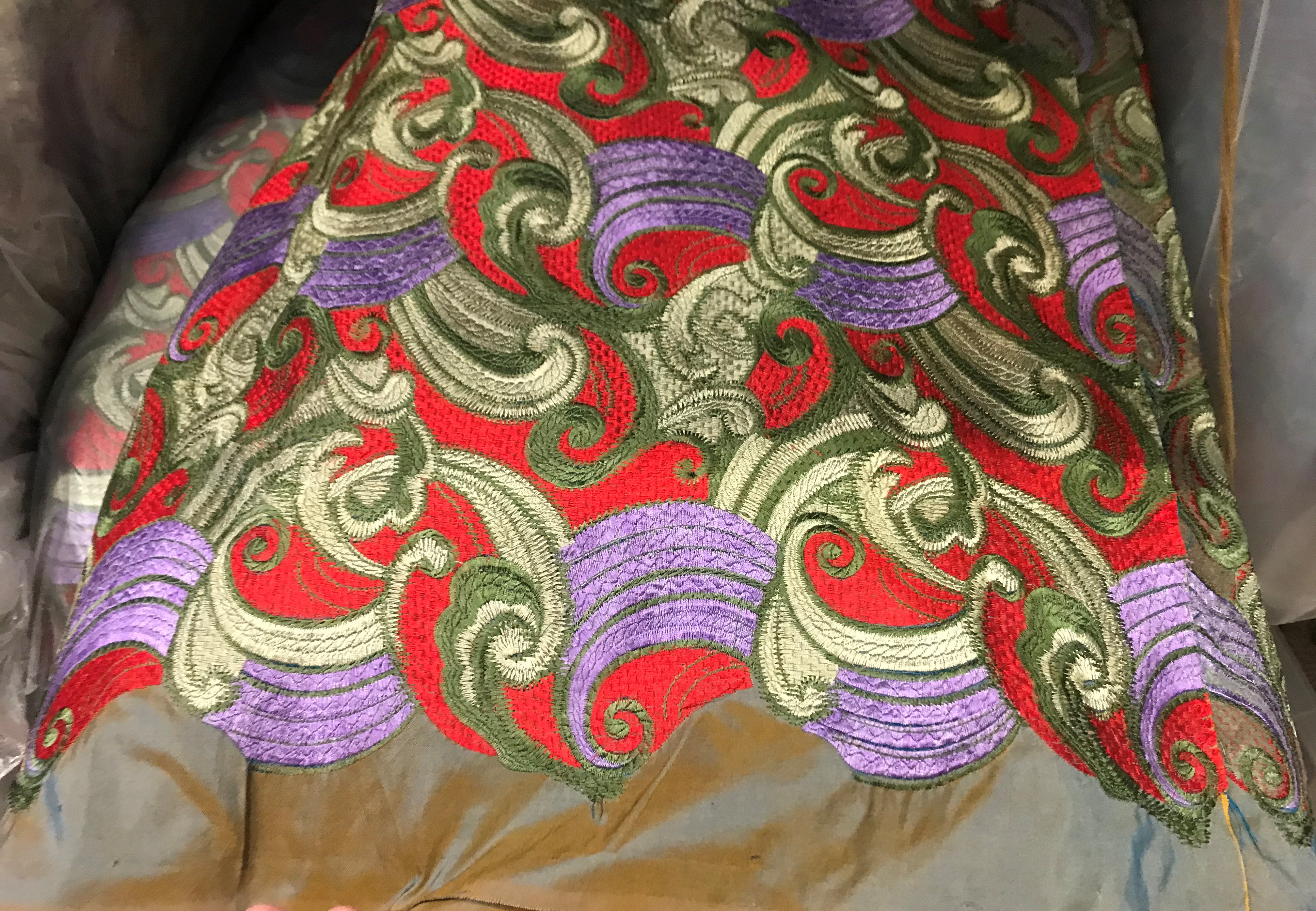 A large quantity of silk material with embroidered green, purple and red scroll decoration,