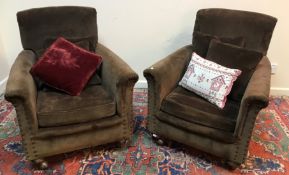 A pair of circa 1900 upholstered and studded scroll arm chairs on squat bun feet to replacement