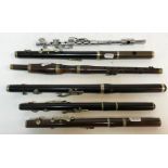 A collection of various woodwind instruments including a silver plated three section flute stamped