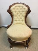 A Victorian carved walnut framed button back salon chair with circular seat on carved cabriole legs