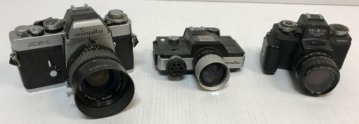 A collection of five Minolta cameras including an XE-1, SRT101, Mark II 110 zoom SLR,