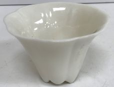 A Chinese blanc de chine wine cup of ribbed design with prunus blossom relief work decoration,