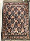An old Persian carpet, the central panel set with repeating hook motifs on a navy ground,