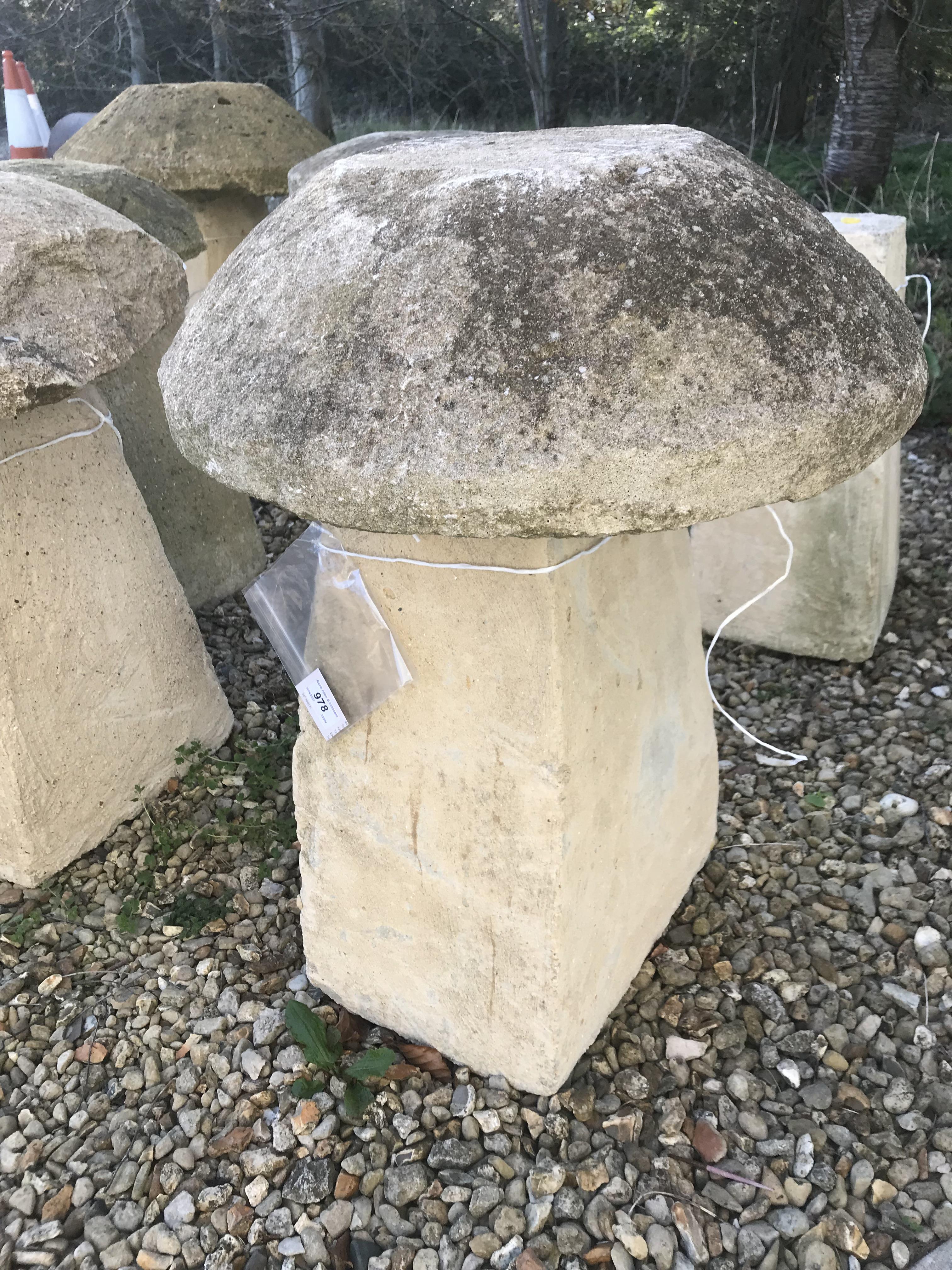 A stone topped staddle stone with weathered composite stone base