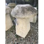 A stone topped staddle stone with weathered composite stone base