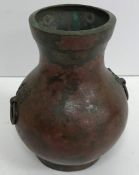 An early Chinese patinated bronze baluster shaped vase with stylised elephant mask ring handles,