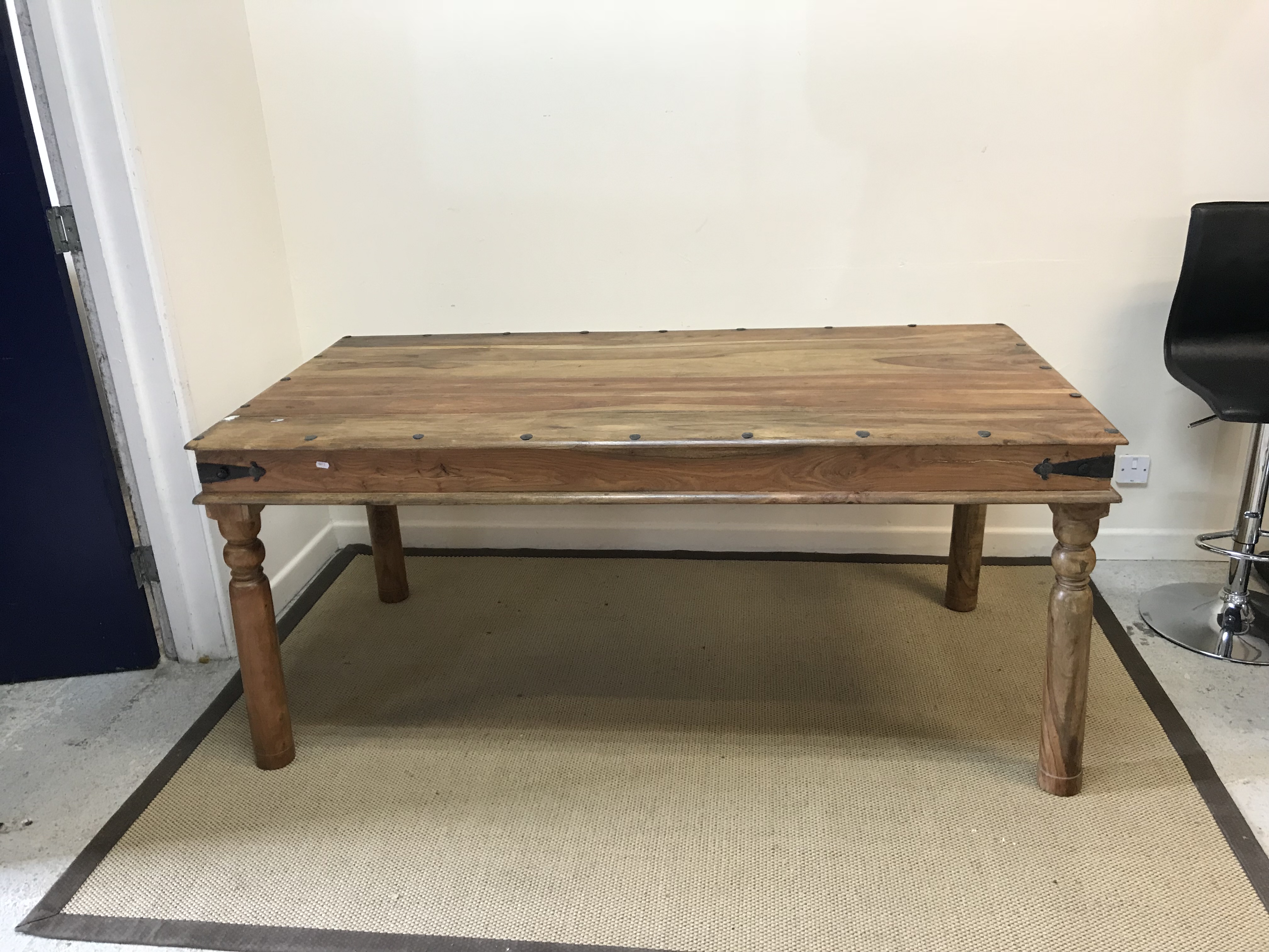 An Indian hardwood and studded dining table, the plank top over a plain frieze,