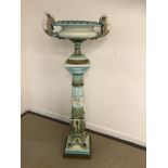 An early 20th Century majolica jardiniere on stand in blues and greens,