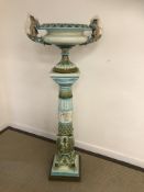 An early 20th Century majolica jardiniere on stand in blues and greens,