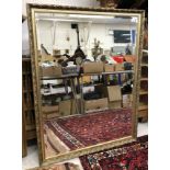 A modern gilt framed wall mirror with scrolling foliate design enclosing a bevel edged plate 126 cm