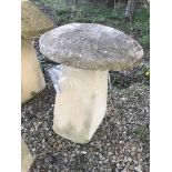 A stone topped staddle stone with weathered composite stone base