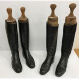 Two pairs of black hunting boots with wooden trees