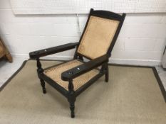 A 20th Century teak framed plantation chair with caned back and seat 67 cm wide x 102 cm depth x 96