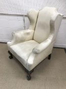 An early 20th Century wing back scroll arm armchair,