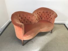 An early 20th Century conversation seat with buttoned back in orange velour upholstery raised on