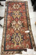 A vintage Caucasian runner, the central panel set with geometric medallions on a red ground,