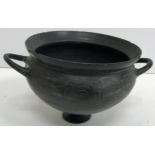 An Etruscan black glazed terracotta bowl with two side handles, raised on a small circular foot 12.