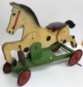 An early 20th Century wooden painted spring-loaded rocking horse toy on wheels bearing remains of