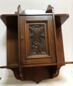 A circa 1900 mahogany wall cabinet with single door carved with a foliate design flanked by open