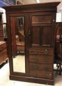 A circa 1900 walnut wardrobe compactum with mirrored door enclosing a hanging space over a small