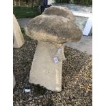 A stone topped staddle stone with weathered composite stone base