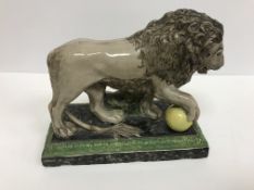 An early 19th Century Staffordshire polychrome decorated pottery figure of a lion with ball,