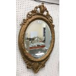 A circa 1900 gilt and gesso framed oval wall mirror in the Regency taste with bevel edged plate,
