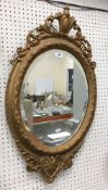 A circa 1900 gilt and gesso framed oval wall mirror in the Regency taste with bevel edged plate,