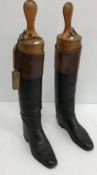 A pair of black and tan hunting boots with wooden trees
