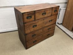 A Victorian teak military chest in two parts, typically brass bound and with flush handles,