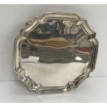 A George V silver card tray with pie-crust rim on four scroll feet (by Goldsmiths & Silversmiths of