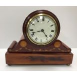 A mahogany and inlaid cased mantel clock, of drum form, on a scrollwork decorated base, 22 cm high,