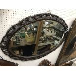 A 20th Century carved oak framed oval wall mirror in the Rococo taste with bevel edge plate 104 cm