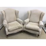 A pair of modern upholstered wingback scroll armchairs in the Victorian style raised on turned and