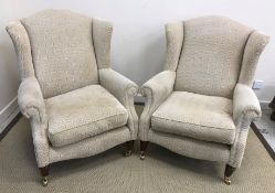 A pair of modern upholstered wingback scroll armchairs in the Victorian style raised on turned and