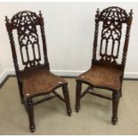 A pair of Victorian oak panel seated hall chairs in the Gothic style with shield shaped seats on