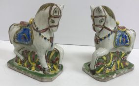 A pair of polychrome glazed faience pottery figures of ceremonial horses with ornate saddles,
