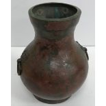 An early Chinese patinated bronze baluster shaped vase with stylised elephant mask ring handles,