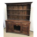 A 20th Century oak dresser in the 18th Century manner with plate rack over three drawers above
