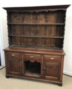 A 20th Century oak dresser in the 18th Century manner with plate rack over three drawers above