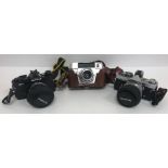 A collection of various cameras to include a Zoki 4K, Regula, Olympus OM-4, Olympus OM-2,