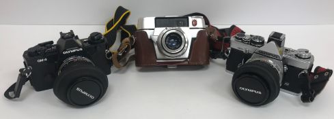 A collection of various cameras to include a Zoki 4K, Regula, Olympus OM-4, Olympus OM-2,