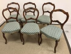 A set of six Victorian walnut framed and carved dining chairs with upholstered seats on cabriole