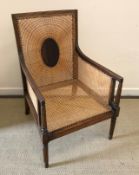 A 19th Century mahogany framed and caned bergère armchair with reeded decoration raised on turned