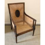 A 19th Century mahogany framed and caned bergère armchair with reeded decoration raised on turned