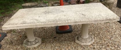 A cast concrete garden table raised on two pillars,