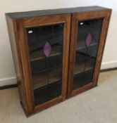 A circa 1900 oak two door display cabinet with leaded glazed panels enclosing adjustable shelving