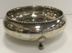 A sterling silver bowl with applied decoration raised on three claw feet stamped "Sterling silver"